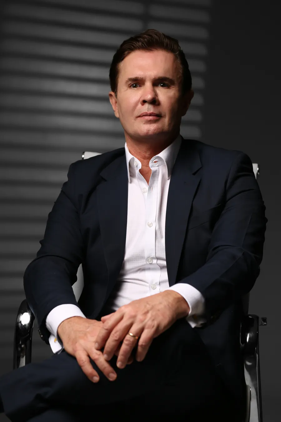 Dr. Marcelo Navarro, cirurgião plástico, sentado de terno escuro